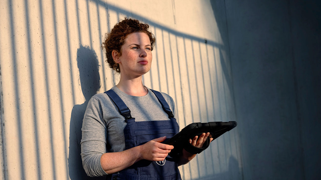Servicemedewerker staat tegen een muur geleund met een tablet in haar hand